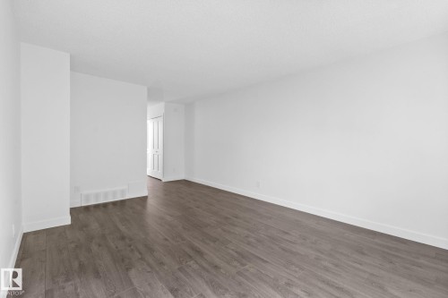Open living area featuring wood-finish flooring, white baseboards, crisp white walls, and a recessed air vent - 2832 135 Avenue, Edmonton, AB - Indoor Photo Showing Other Room