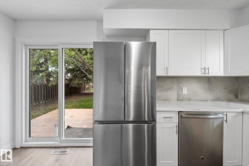 Kitchen featuring white cabinetry with brushed nickel hardware, a stainless steel French-door refrigerator, and a stainless steel dishwasher - 2832 135 Avenue, Edmonton, AB - Indoor Photo Showing Kitchen