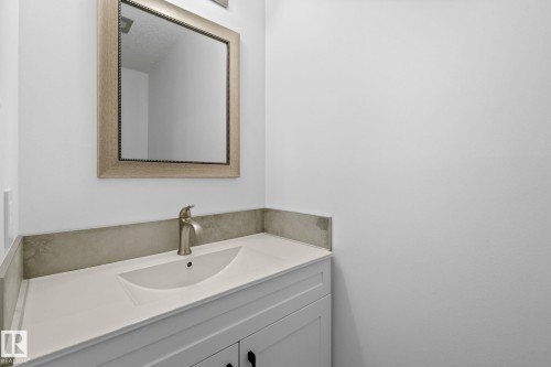 White vanity with panel detailing, integrated sink, and brushed nickel single-handle faucet - 2832 135 Avenue, Edmonton, AB - Indoor Photo Showing Bathroom