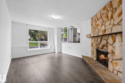 Stone-clad fireplace with a hearth and mantle, wood-finish flooring, and white walls - 2832 135 Avenue, Edmonton, AB - Indoor Photo Showing Living Room With Fireplace