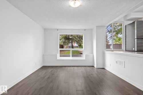 Spacious room featuring wood-finish flooring, crisp white walls, and a large window with white trim - 2832 135 Avenue, Edmonton, AB - Indoor Photo Showing Other Room