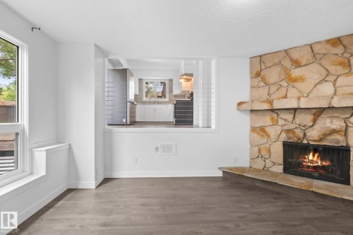 Living area featuring a stone-clad fireplace and wood-finish flooring - 2832 135 Avenue, Edmonton, AB - Indoor Photo Showing Other Room With Fireplace