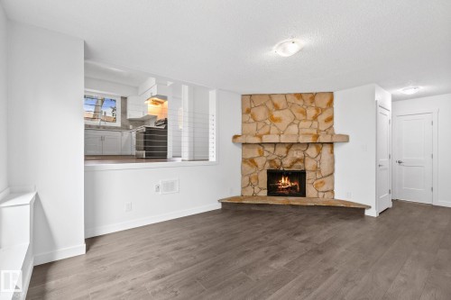 Corner stone fireplace with a substantial hearth and mantel, complemented by wood-finish flooring - 2832 135 Avenue, Edmonton, AB - Indoor Photo Showing Living Room With Fireplace