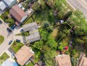 Aerial perspective showcasing a property with a distinctive L-shaped roofline, an expansive green space, mature trees, and a paved driveway - 2832 135 Avenue, Edmonton, AB  - Outdoor With View 