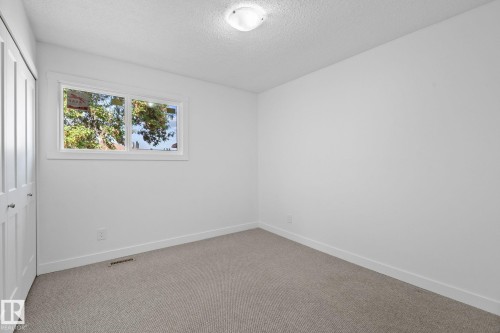 Carpeted room featuring a white-framed window, bi-fold closet doors, white walls, and a flush-mount ceiling light fixture - 2832 135 Avenue, Edmonton, AB - Indoor Photo Showing Other Room