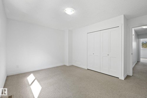 Carpeted room featuring white walls, a flush-mount ceiling light fixture, and a bi-fold closet with white doors - 2832 135 Avenue, Edmonton, AB - Indoor Photo Showing Other Room