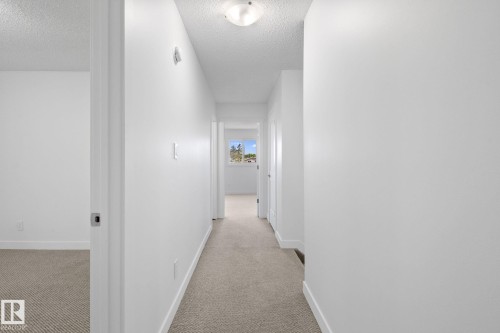 Hallway with light-colored carpeting, white baseboards, and bright white painted walls - 2832 135 Avenue, Edmonton, AB - Indoor Photo Showing Other Room