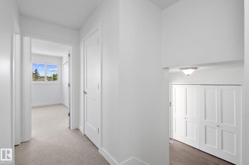 Hallway featuring light neutral carpeting, white trim, and white paneled doors - 2832 135 Avenue, Edmonton, AB - Indoor Photo Showing Other Room