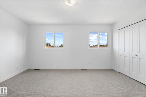 Carpeted interior space featuring two windows, white walls, and bi-fold closet doors - 2832 135 Avenue, Edmonton, AB - Indoor Photo Showing Other Room