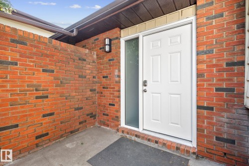 Entryway featuring a panel door, frosted sidelight, and brick exterior - 2832 135 Avenue, Edmonton, AB - Outdoor With Exterior