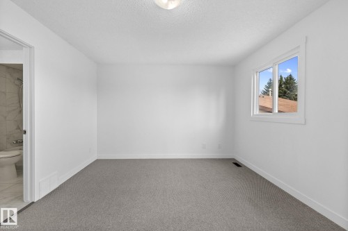 Carpeted bedroom with white walls, a single window, and a door opening to a tiled bathroom - 2832 135 Avenue, Edmonton, AB - Indoor Photo Showing Other Room