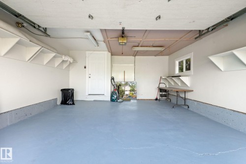 Garage featuring a light blue floor coating, white interior walls, built-in shelving, a full-light window, and a white entry door - 2832 135 Avenue, Edmonton, AB - Indoor Photo Showing Garage