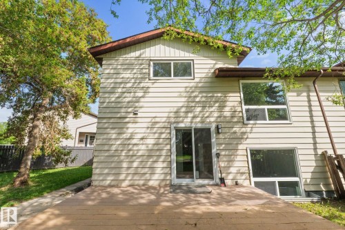 Exterior featuring horizontal siding, multiple windows, a second-story window, and a ground-level patio door opening onto a private deck - 2832 135 Avenue, Edmonton, AB - Outdoor