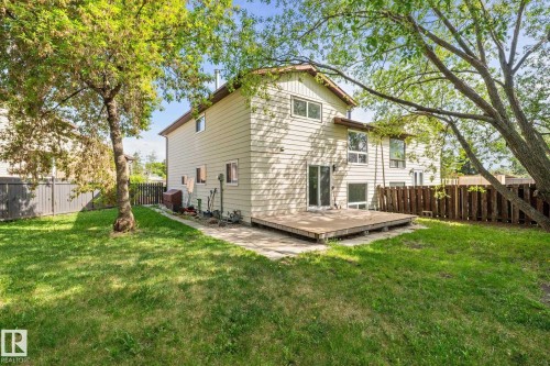 Expansive rear yard featuring a wooden deck, sliding glass doors, and mature trees providing natural shade - 2832 135 Avenue, Edmonton, AB - Outdoor