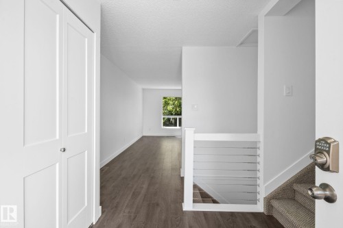 Entryway featuring wood-finish flooring, a white paneled closet door, a staircase with carpeting and horizontal railing, and a window with natural light - 2832 135 Avenue, Edmonton, AB - Indoor Photo Showing Other Room