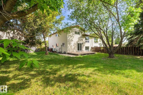 Spacious backyard with mature trees, a manicured lawn, and a wooden deck - 2832 135 Avenue, Edmonton, AB - Outdoor