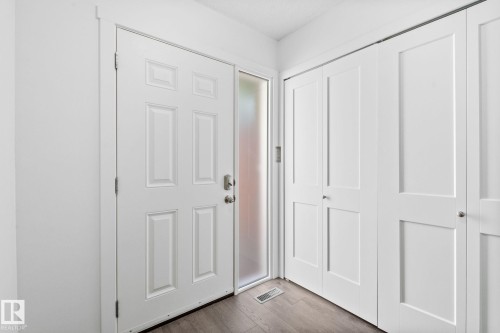 Entryway featuring a paneled door with frosted sidelight, wood-finish flooring, and white bifold closet doors - 2832 135 Avenue, Edmonton, AB - Indoor Photo Showing Other Room