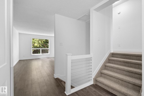 Bright interior space featuring wood-finish flooring, white walls, and a large window with exterior greenery - 2832 135 Avenue, Edmonton, AB - Indoor Photo Showing Other Room