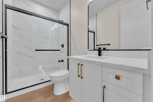 Bathroom featuring a walk-in shower with black-framed glass enclosure, white marble-look wall tiles, and black fixtures - 3602 44 Avenue, Beaumont, AB 