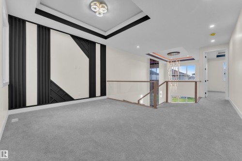 Spacious carpeted hallway featuring a decorative wall panel with black geometric accents and recessed lighting - 3602 44 Avenue, Beaumont, AB 