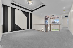 Spacious carpeted hallway featuring a decorative wall panel with black geometric accents and recessed lighting - 