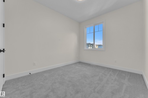 Bright interior space featuring light gray carpeting, white walls, and a white-framed window - 3602 44 Avenue, Beaumont, AB 