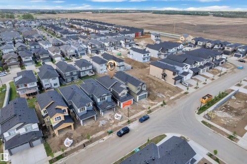Aerial perspective of a developing residential community, showcasing multiple detached homes with dark shingle roofing - 3602 44 Avenue, Beaumont, AB 