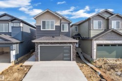 Contemporary residence featuring a two-car garage with frosted glass panels, a concrete driveway, mixed siding, and stone accents - 