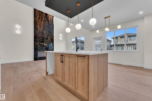 Kitchen island featuring light wood-finish cabinetry, a white countertop, and a black faucet - 3602 44 Avenue, Beaumont, AB 