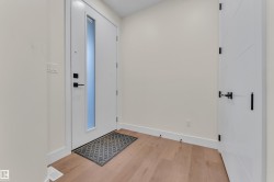Entryway featuring light wood-finish flooring, a contemporary white door with a frosted vertical glass panel, and matte black hardware - 