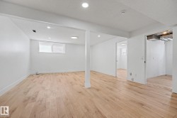 Spacious room featuring wood-finish flooring, white walls, and recessed lighting - 
