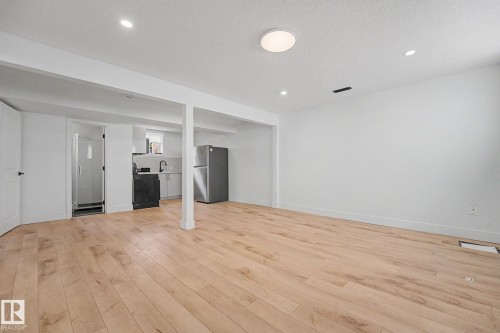 Open-concept living space featuring wood-finish flooring, recessed lighting, and a white color palette - 11914 124 Street, Edmonton, AB 