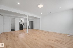 Open-concept living space featuring wood-finish flooring, recessed lighting, and a white color palette - 