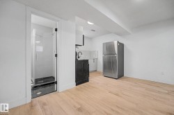 Kitchenette featuring a stainless steel refrigerator, white countertops, and dark lower cabinetry - 