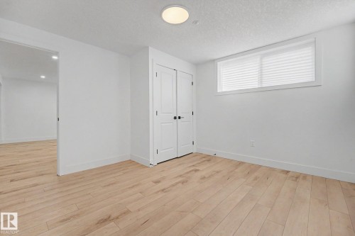 Bright room featuring light wood-finish flooring, white walls, and a contemporary flush-mount ceiling light - 11914 124 Street, Edmonton, AB 