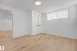 Bright room featuring light wood-finish flooring, white walls, and a contemporary flush-mount ceiling light - 