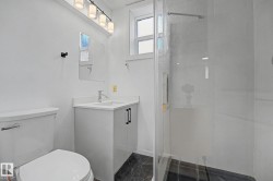 Bathroom featuring a glass-enclosed shower, a white vanity with a single sink, and a modern light fixture - 