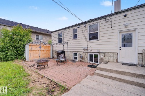 Backyard patio area featuring a brick paver surface, concrete steps, and a white exterior door - 11914 124 Street, Edmonton, AB 