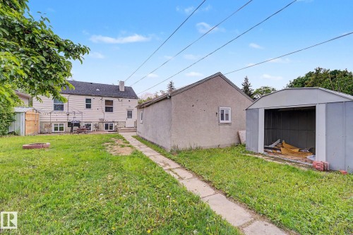 Expansive grassy yard with concrete pathway, detached garage, and metal shed - 11914 124 Street, Edmonton, AB 