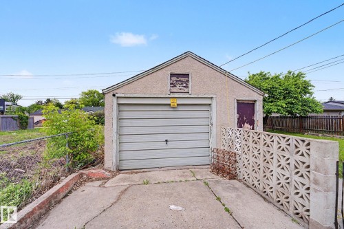 Detached garage with a roll-up door, stucco exterior, and gable roofline - 11914 124 Street, Edmonton, AB 