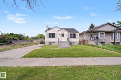 Traditional single-story residence featuring light-colored siding, a dark shingled roof, and a prominent front entrance with a porch and steps - 