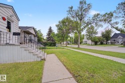 Exterior siding with a raised porch, featuring black wrought iron railings and concrete steps - 