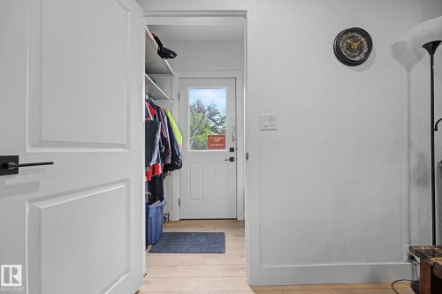 Entryway featuring a white paneled door with matte black hardware, light wood-finish flooring, and white painted walls - 11914 124 Street, Edmonton, AB 