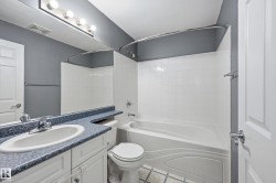 Bathroom featuring a white vanity with cabinet storage, a speckled blue countertop, an undermount sink, and a chrome faucet - 