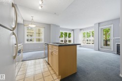 Open-concept kitchen and living area featuring a central island with an undermount sink and stainless steel dishwasher - 