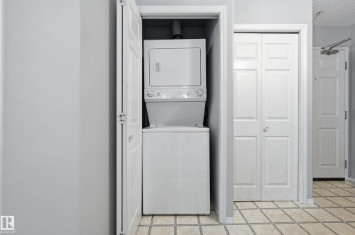 Dedicated laundry closet featuring a white stackable washer and dryer unit - 203 11103 84 Avenue, Edmonton, AB 