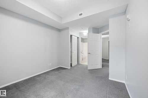 Spacious room with light gray walls, gray carpeting, and white trim - 203 11103 84 Avenue, Edmonton, AB 