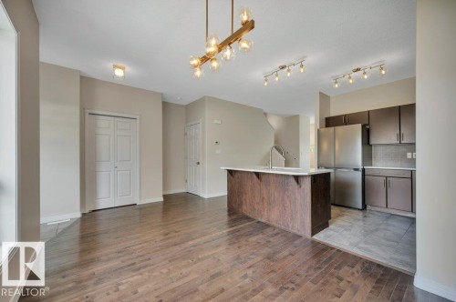 Open-concept living area featuring rich wood-finish flooring - 14 4367 Veterans Way, Edmonton, AB 