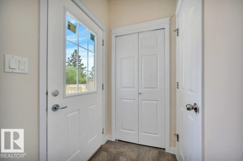 Entryway featuring wood-finish flooring, white paneled doors, and a glass-paned exterior door - 14 4367 Veterans Way, Edmonton, AB 