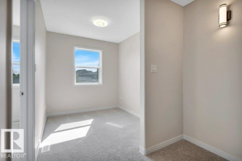 Neutral-toned room featuring a double-hung window, light gray carpeting, and a flush-mount ceiling light - 14 4367 Veterans Way, Edmonton, AB 